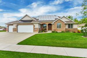 View of front of home featuring a front yard, a garage, and solar panels