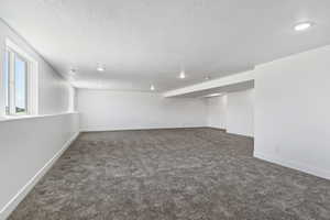 Empty room featuring a textured ceiling and dark carpet