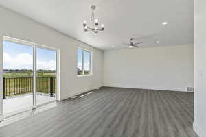 Spare room featuring hardwood / wood-style flooring and ceiling fan with notable chandelier