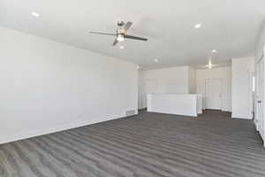 Unfurnished living room featuring dark wood-type flooring and ceiling fan