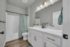 Full bathroom featuring wood-type flooring, oversized vanity, toilet, and shower / bath combination with curtain