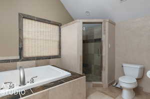 Bathroom with tile floors, vaulted ceiling, shower with separate bathtub, and toilet