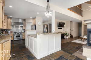 Kitchen featuring stainless steel appliances, dark tile flooring, wall chimney exhaust hood, and pendant lighting