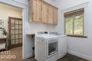 Washroom with washing machine and dryer, tile flooring, and cabinets