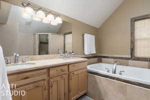 Bathroom featuring large vanity, plus walk in shower, vaulted ceiling, and dual sinks