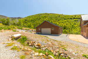 Exterior space with a garage, a mountain view, and an outdoor structure