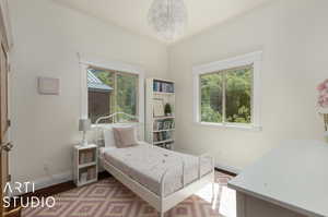 Bedroom featuring an inviting chandelier, hardwood / wood-style flooring, and multiple windows