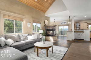 Living room featuring a stone fireplace, wood ceiling, dark wood-type flooring, a notable chandelier, and high vaulted ceiling