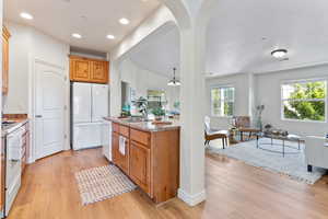 Kitchen with light hardwood / wood-style floors, sink, white appliances, and an inviting chandelier