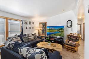 Living room featuring tile flooring, plenty of natural light, and vaulted ceiling