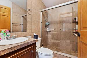 Bathroom with a shower with door, vanity, and toilet