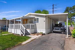 Manufactured / mobile home featuring a front lawn and a carport