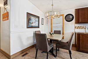 Tiled dining area with an inviting chandelier and vaulted ceiling