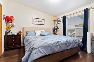 Bedroom with dark hardwood / wood-style flooring and lofted ceiling