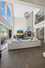 Living room featuring high vaulted ceiling, a fireplace, a chandelier, and dark wood-type flooring