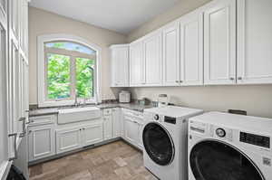 Laundry room featuring sink, washer and clothes dryer, cabinets, and light tile floors