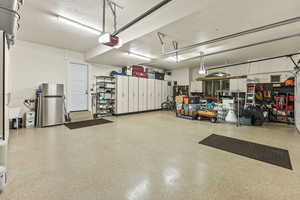 Garage featuring a garage door opener and stainless steel fridge