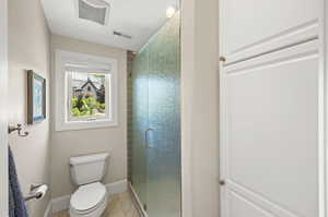 Bathroom with walk in shower, tile flooring, a textured ceiling, and toilet