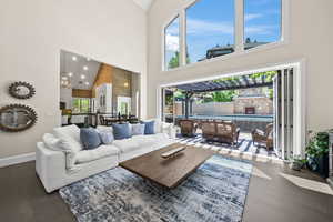 Living room featuring high vaulted ceiling, a wealth of natural light, dark wood-type flooring, and a chandelier