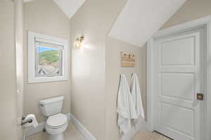 Bathroom featuring tile flooring, toilet, and vaulted ceiling