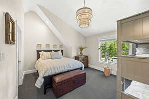 Bedroom with lofted ceiling, an inviting chandelier, and dark carpet