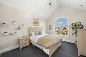 Carpeted bedroom with a notable chandelier and high vaulted ceiling