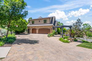 View of front of property featuring a garage and a pergola