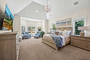 Carpeted bedroom featuring high vaulted ceiling, multiple windows, and an inviting chandelier