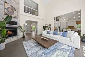 Living room with high vaulted ceiling, a fireplace, a chandelier, and dark wood-type flooring