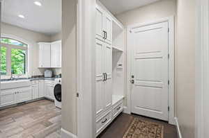 Mudroom featuring sink, washer / dryer, and wood-type flooring