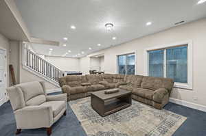 Carpeted living room featuring a textured ceiling