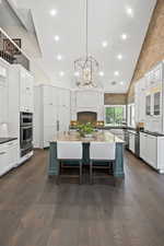 Kitchen featuring an island with sink, white cabinetry, and dark wood-type flooring