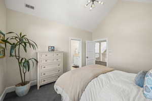 Bedroom with high vaulted ceiling, ensuite bathroom, and dark colored carpet