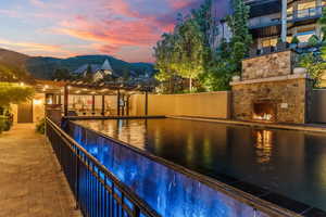 Pool at dusk with a patio area and a mountain view