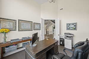 Office with dark wood-type flooring and a towering ceiling