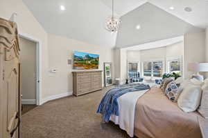 Carpeted bedroom featuring a notable chandelier and high vaulted ceiling