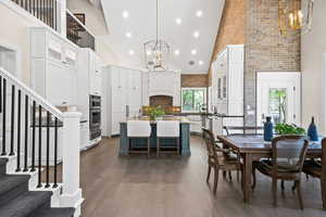 Dining area featuring high vaulted ceiling, sink, dark hardwood / wood-style floors, and an inviting chandelier