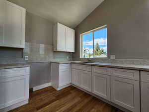 Kitchen featuring white cabinets, vaulted ceiling