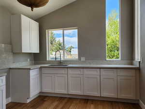 Kitchen with sink, white cabinets, and vaulted ceiling