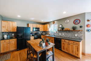 Kitchen featuring backsplash, black appliances, and light wood-type flooring