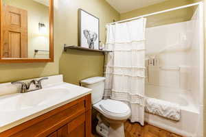 Full bathroom with hardwood / wood-style floors, oversized vanity, toilet, and shower / bath combo