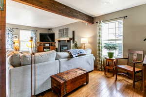 Living room with beamed ceiling, hardwood / wood-style flooring, a fireplace, and plenty of natural light