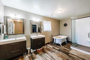 Bathroom with dual bowl vanity, separate shower and tub, and wood-type flooring