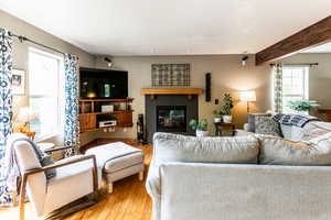 Living room with a fireplace, beamed ceiling, and hardwood / wood-style floors