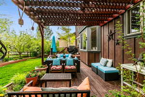 Wooden terrace featuring a pergola, an outdoor hangout area, and a lawn