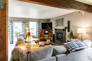 Living room with beam ceiling, a tile fireplace, and hardwood / wood-style floors