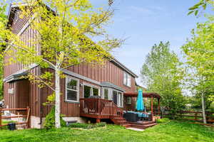 Rear view of property featuring a lawn and a wooden deck, fenced for the pets, lots of flower boxes.