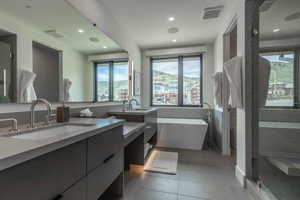 Bathroom with tile flooring, oversized vanity, dual sinks, and plus walk in shower