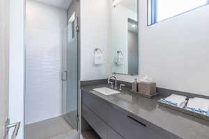 Bathroom featuring a shower with shower door and vanity