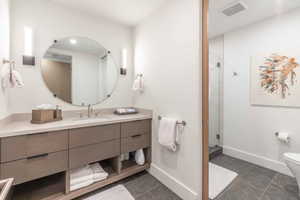 Bathroom with a shower with shower door, oversized vanity, toilet, and tile floors